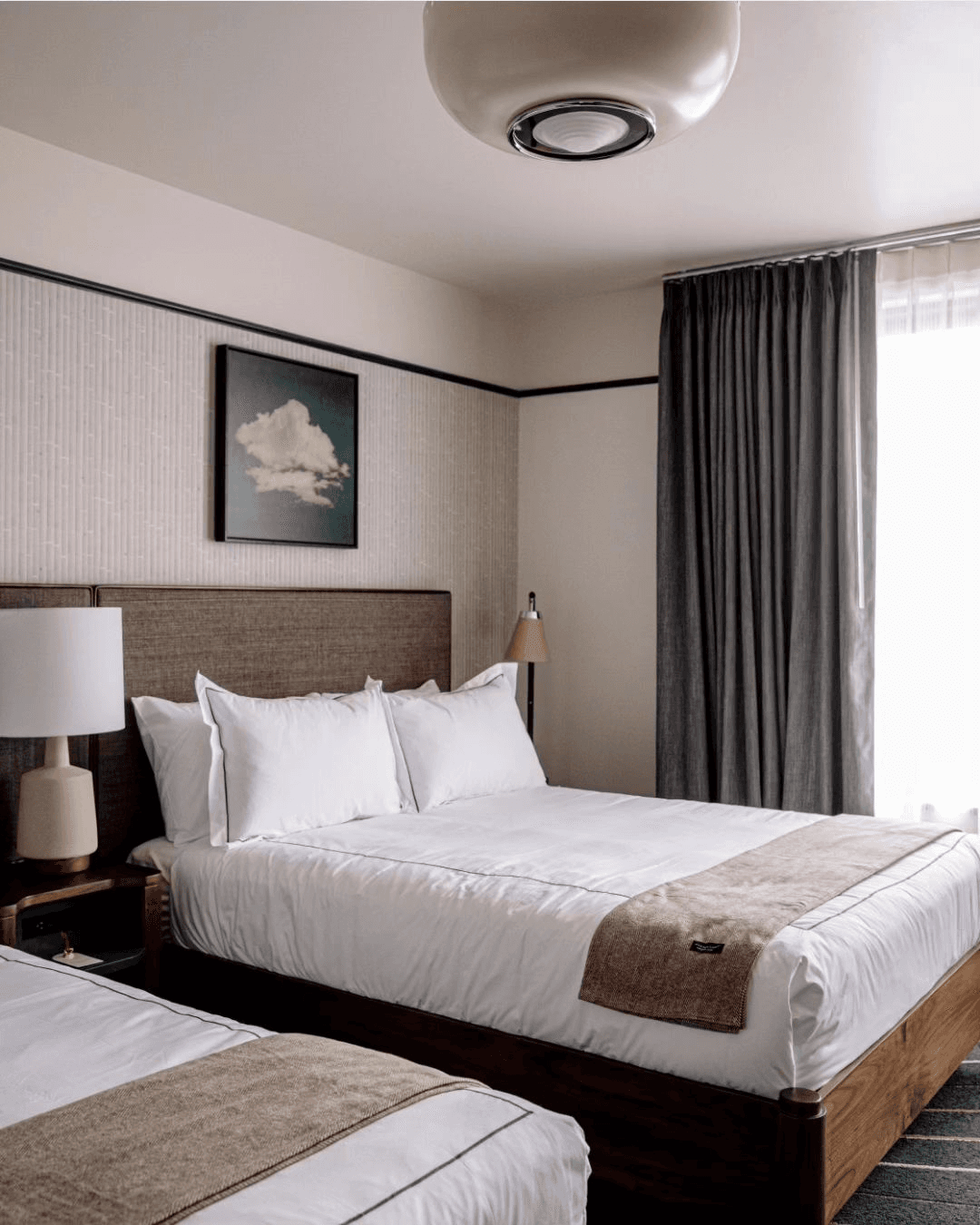 A double queen hotel room with white bedding and neutral details.