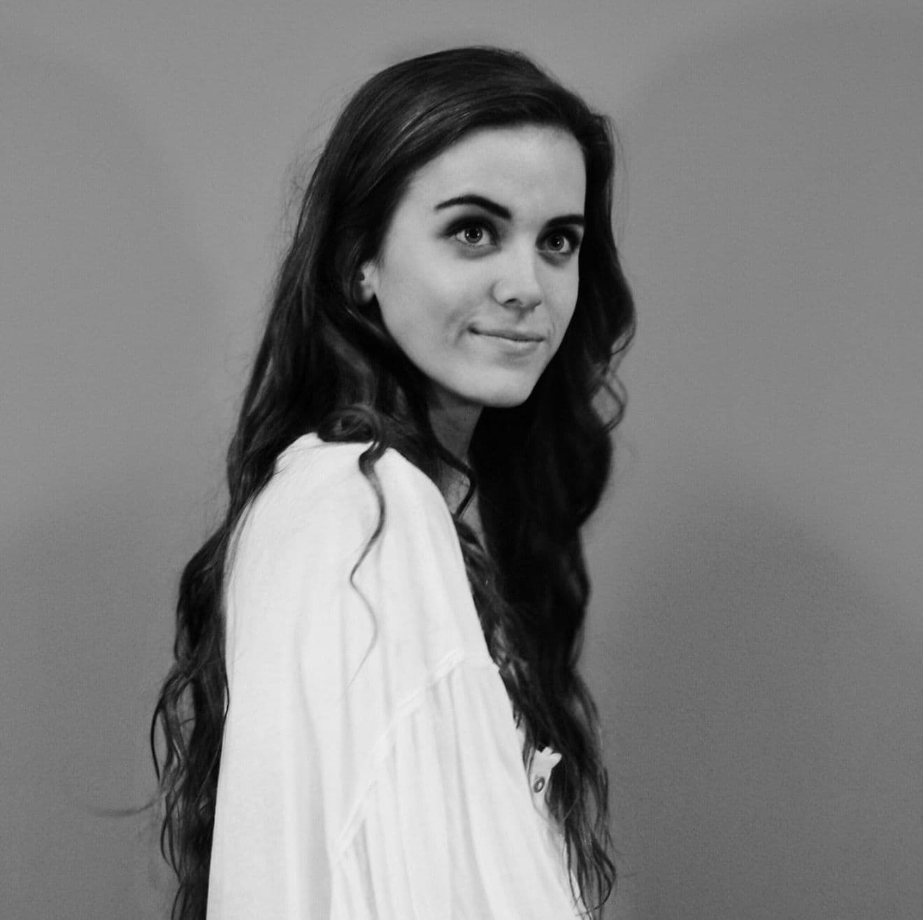 Girl in white blouse smiling for a headshot.