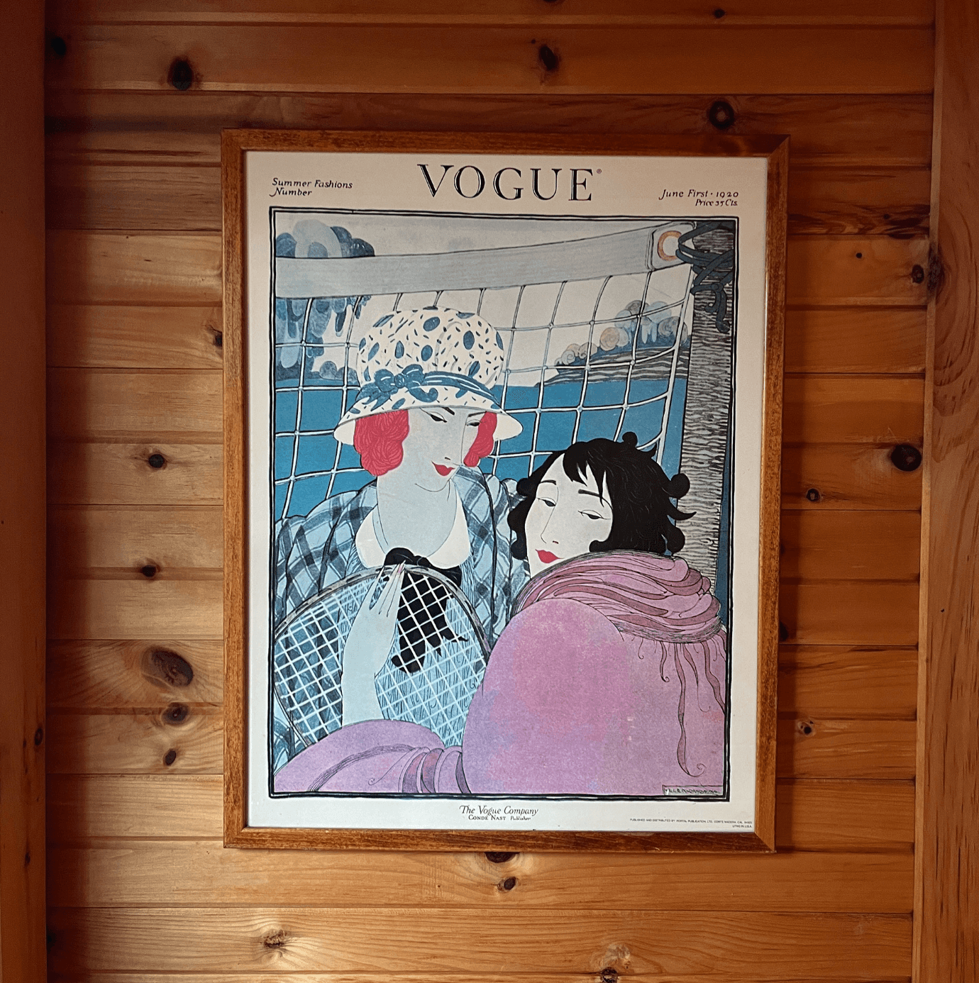 Framed 1920 Vogue illustrated print of two women with a racquet between them, each looking back at the camera.