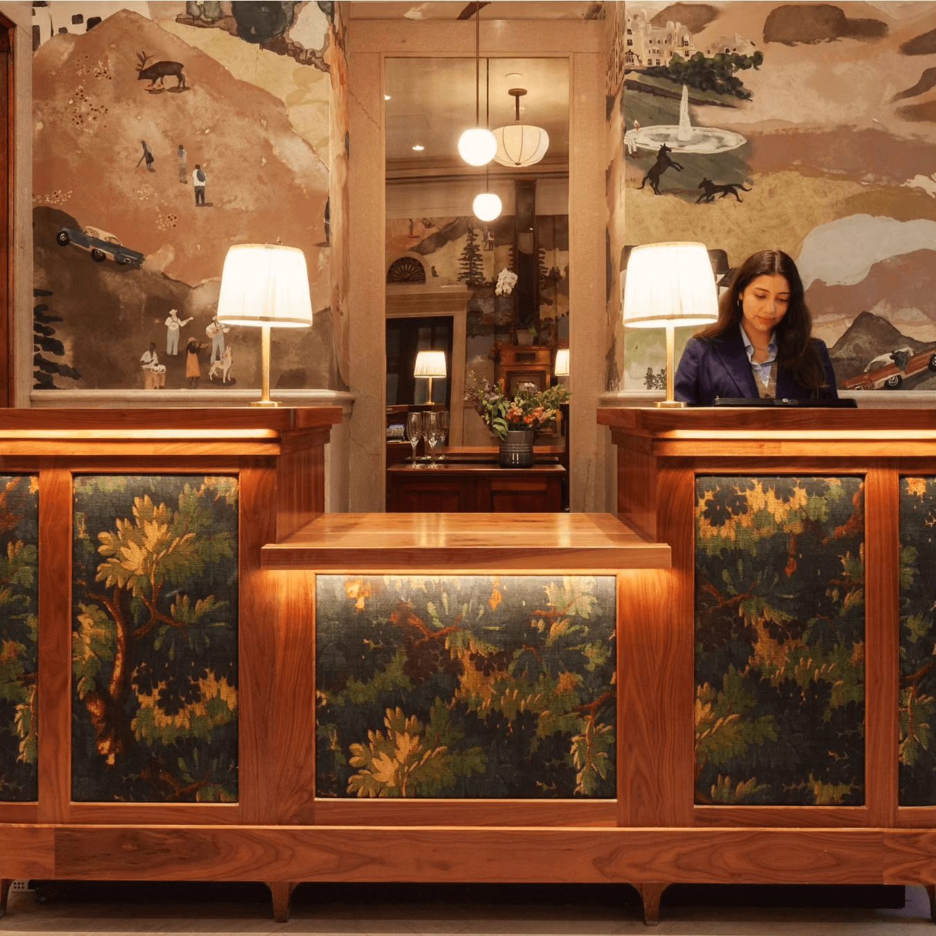 Upholstered lobby counters in historical Art Deco style, with a woman standing behind it.