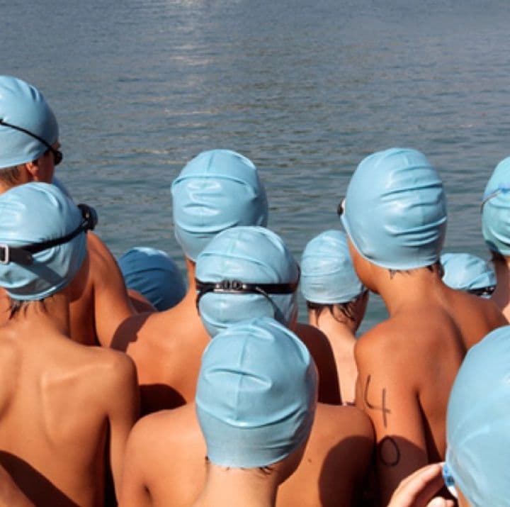 crowd of light blue swim caps clustered on a dock